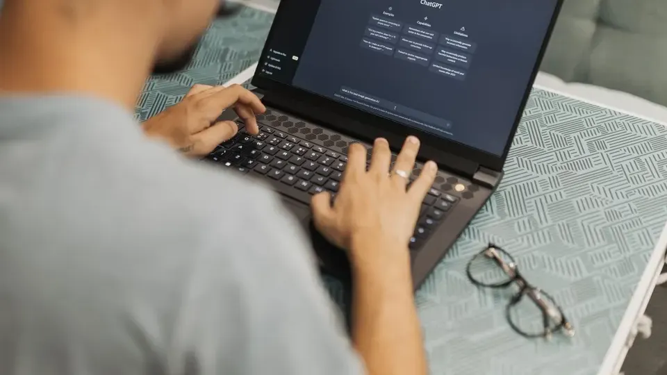 Person using a laptop with an AI chat assistant open, illustrating SEO alongside AI answers