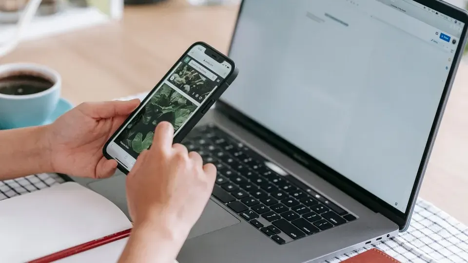 Person browsing on a phone beside a laptop, illustrating website visit tracking