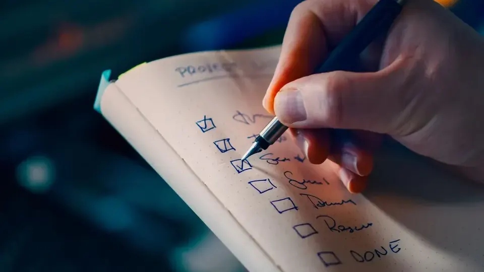 Hand ticking items on a handwritten checklist in a notebook