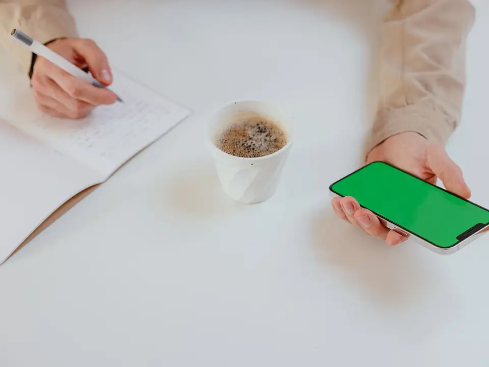 Hands writing notes beside a phone, as when a business follows up a new enquiry from a Google ad