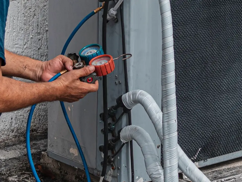Technician checking an outdoor air-conditioner unit with pressure gauges, the kind of home service job a call-led local Google Ads campaign books