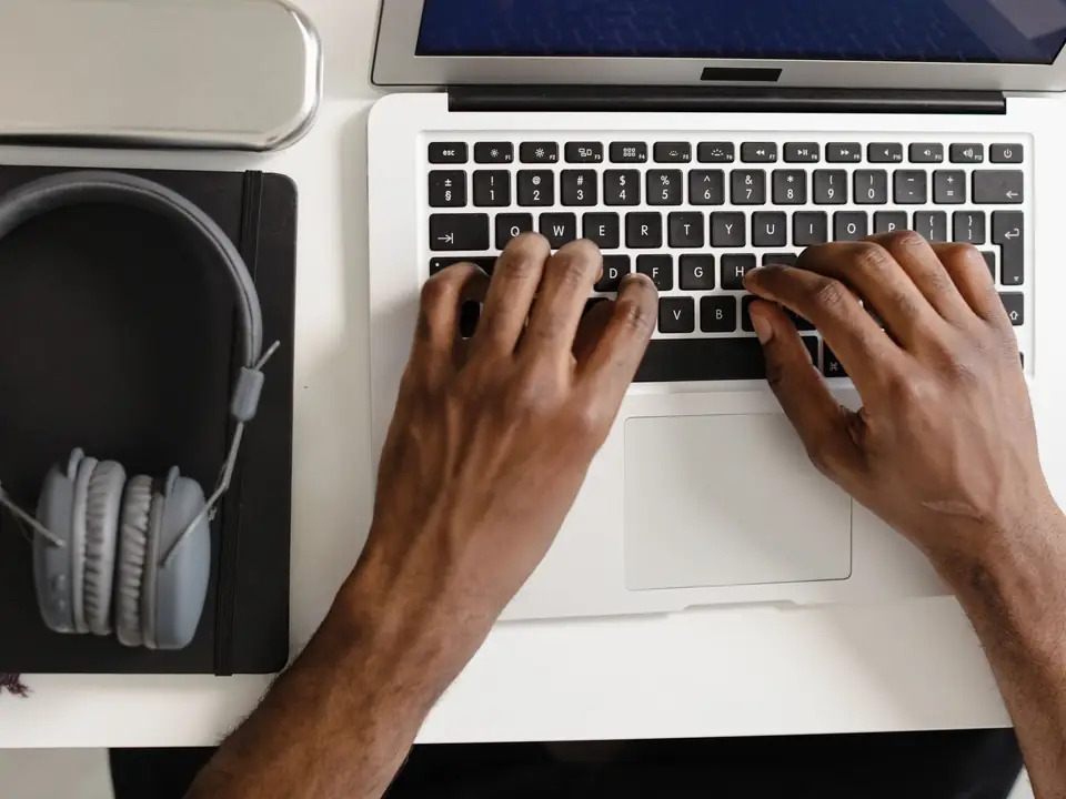 Hands typing on a laptop keyboard beside a notebook, the desk work behind weekly Google Ads management