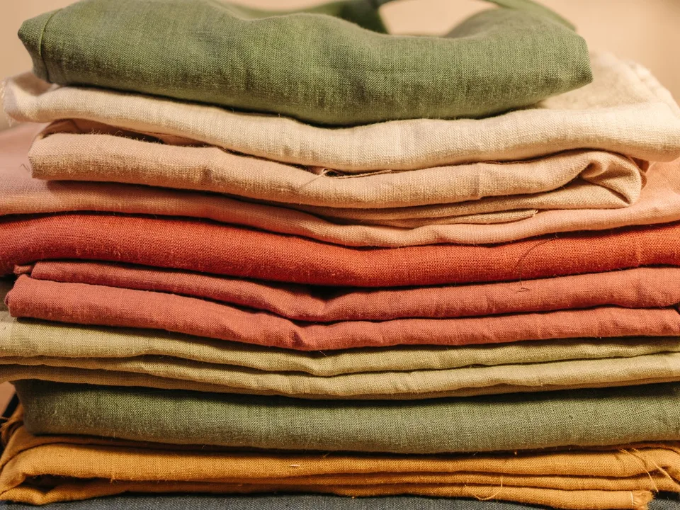 Stack of folded linen garments in earthy colours, the kind of product range an online clothing store lists in its Meta catalogue