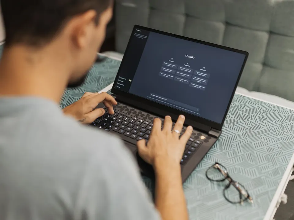 Person typing a question to an AI assistant on a laptop, the way customers now ask AI tools about Coimbatore businesses
