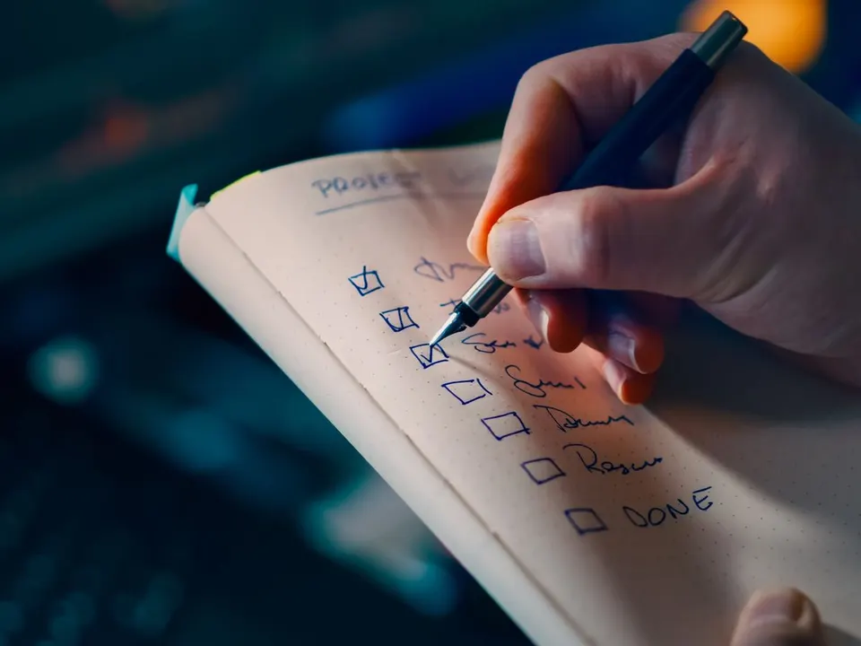 Hand ticking off a priority to-do checklist, like the fix list from a free SEO website check in Coimbatore